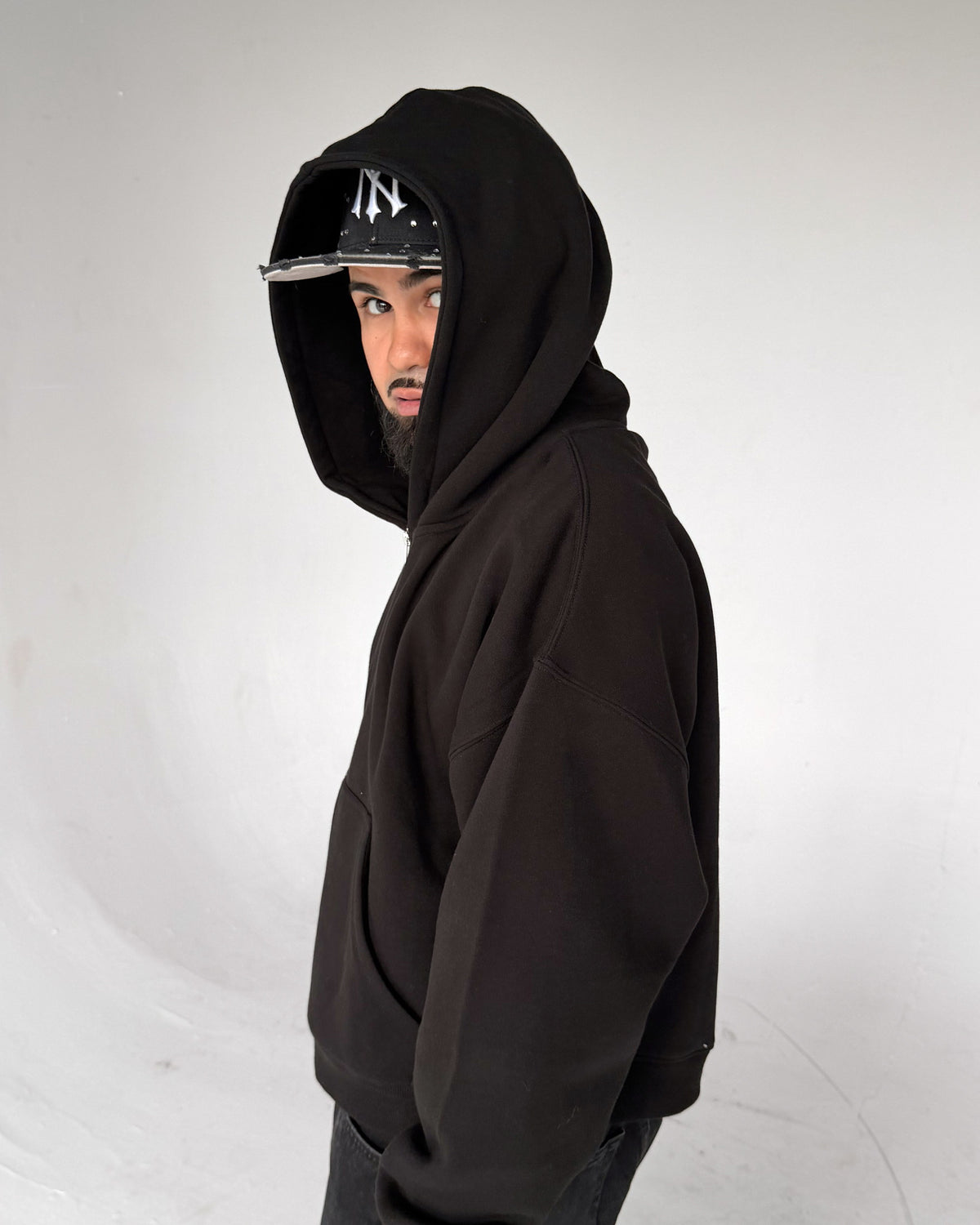 Oversized Crop Zip hoodie in Black, side with the hood up, on a model
